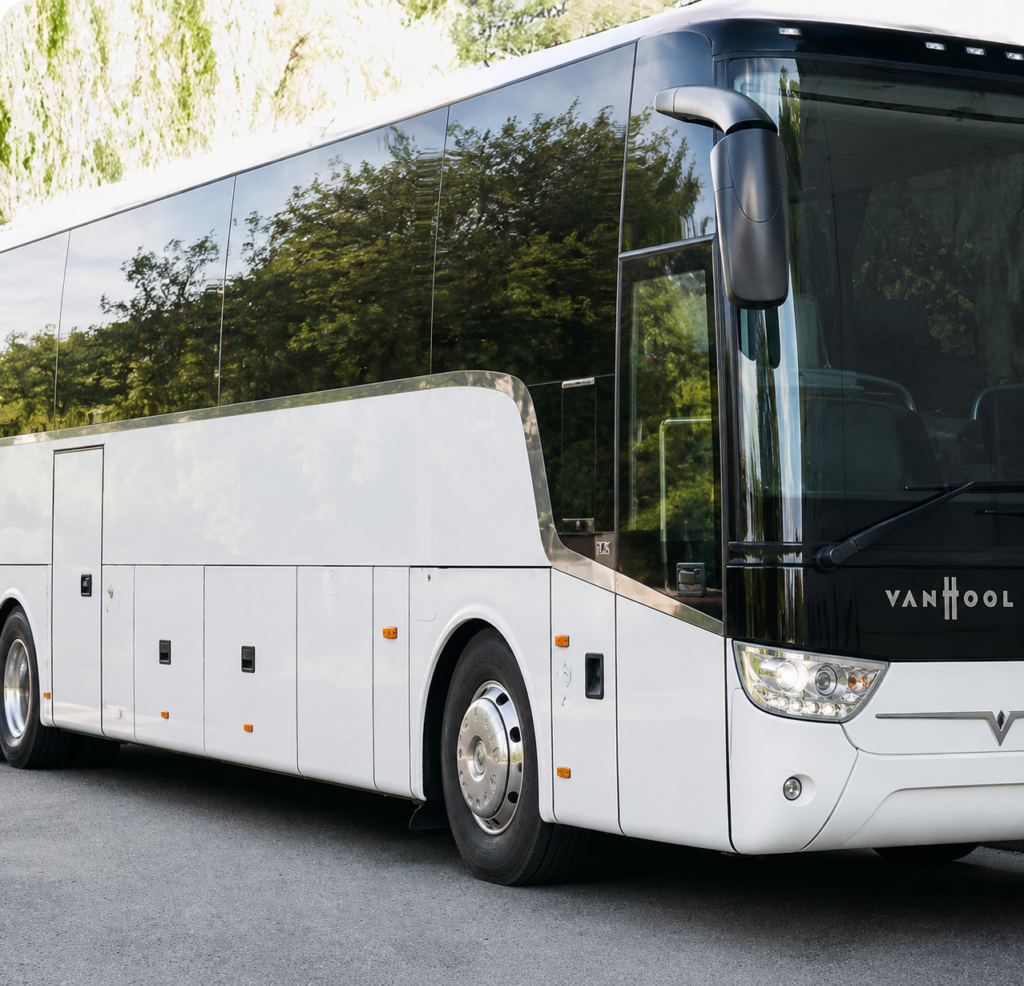 White Van Hool coach bus parked outdoors with tinted windows and no driver visible.